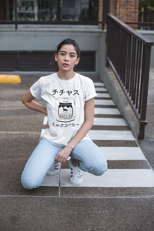 Chichiyasu Milk Coffee graphic tee inspired by the delicious Japanese coffee drink. Cute graphic tee with a black design on a white short-sleeve t-shirt. Cute Japanese graphic tee with Japanese characters and an illustrated design of Chichiyasu Milk Coffee. A cute simple shirt for men or women. Modeled on a cute asian girl hanging out in the street.
